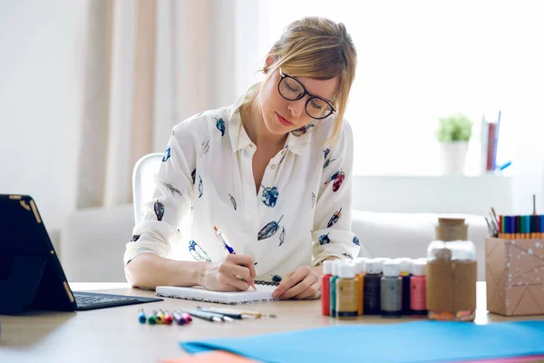 Pofessional 美しい若いデザイナーの女性がオフィスでノートにノートを取ります. — ストック写真