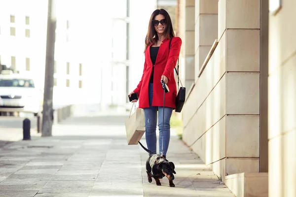 Cool kaunis nuori nainen kävely kun ostoksia kaupungin hänen pieni koira . — kuvapankkivalokuva