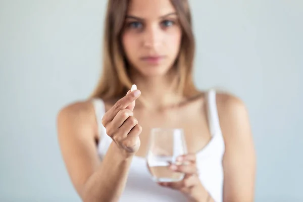 Depressive junge Frau nimmt Tabletten vor grauem Hintergrund. — Stockfoto