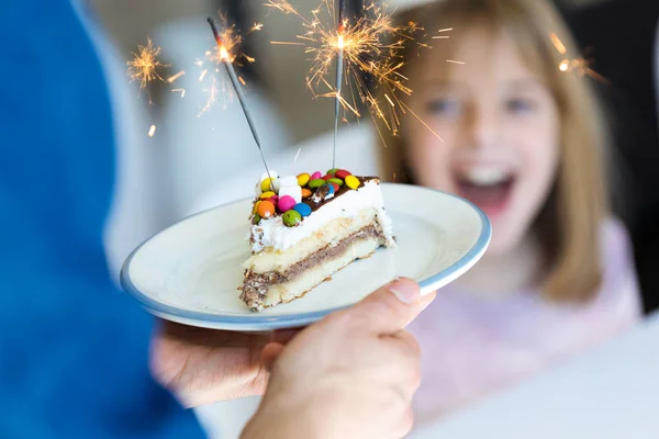 Engraçado menina surpresa e se divertindo com bolo de aniversário na cozinha em casa . — Fotografia de Stock