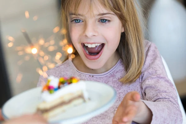 Engraçado menina surpresa e se divertindo com bolo de aniversário na cozinha em casa . — Fotografia de Stock