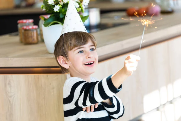 Encantador menino se divertindo com brilhos na cozinha em casa . — Fotografia de Stock