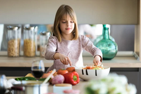 Mooie schattige kleine meid bereidt salade in een kom in de keuken thuis. — Stockfoto