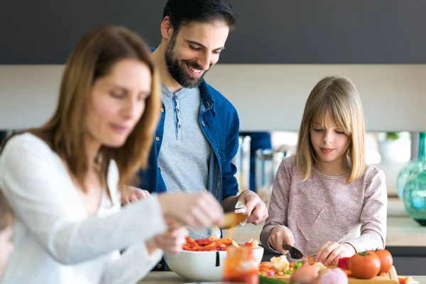 Aantrekkelijke jonge man met haar kleine schattige dochter maken salade samen op keuken thuis. — Stockfoto