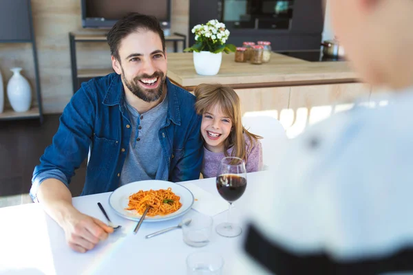 Guapo joven padre y su hermosa divirtiéndose mientras come pasta con salsa de tomate para el almuerzo en la cocina en casa . — Foto de Stock