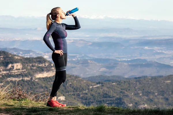 Trail Runner dricksvatten medan du letar landskap från Mountain Peak. — Stockfoto