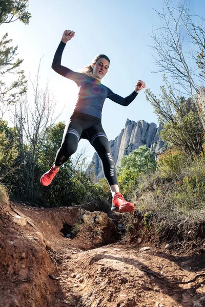 Young fitness woman trail runner running and jumping on rocky mountain. — Stock Photo, Image