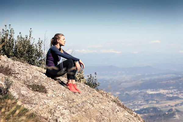 Trail Runner sitter och tar en paus medan du ser landskapet från Mountain Peak. — Stockfoto