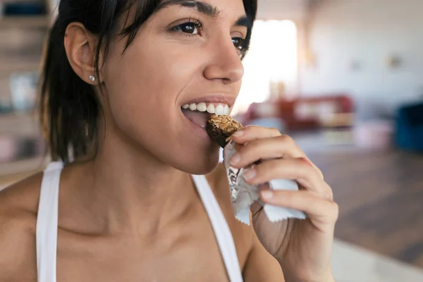 Deportiva joven comiendo muesli snack en casa . — Foto de Stock