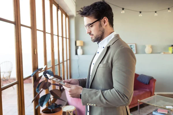 Yakışıklı genç iş adamı ofis salonunda dijital tabletini kullanıyor. — Stok fotoğraf