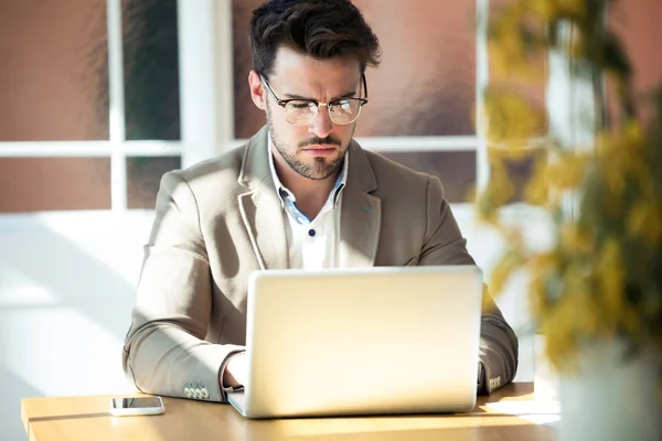 Bonito jovem homem de negócios trabalhando com laptop no escritório . — Fotografia de Stock