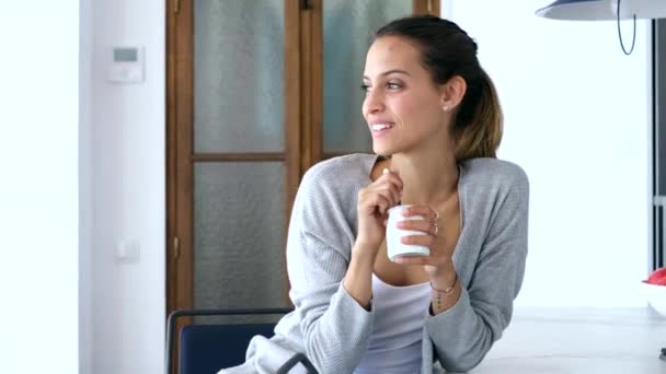 坐在厨房里坐在家里的漂亮年轻女子吃酸奶的视频 — 图库视频影像