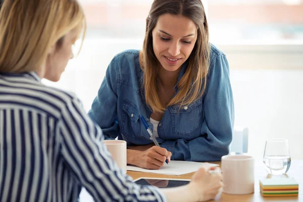 Deux jolies jeunes femmes d'affaires qui travaillent de nouvelles idées au bureau . — Photo