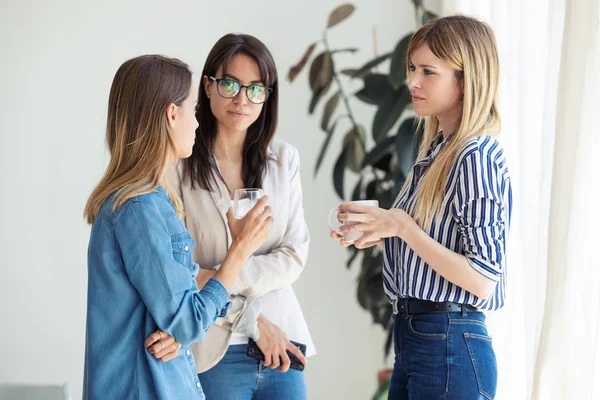 Tres jóvenes y bonitas empresarias tomando café mientras descansan en la oficina . — Foto de Stock