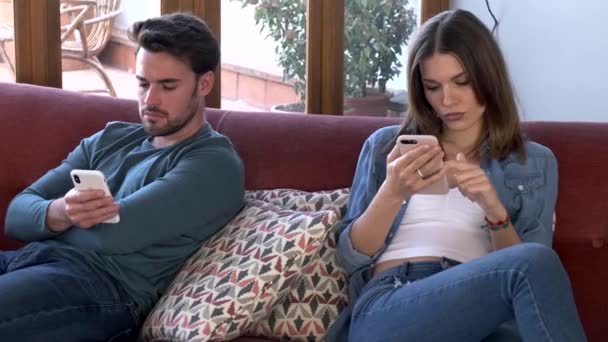 愤怒的年轻夫妇在争吵后用手机互相忽略的视频 而坐在家里的Sofs — 图库视频影像