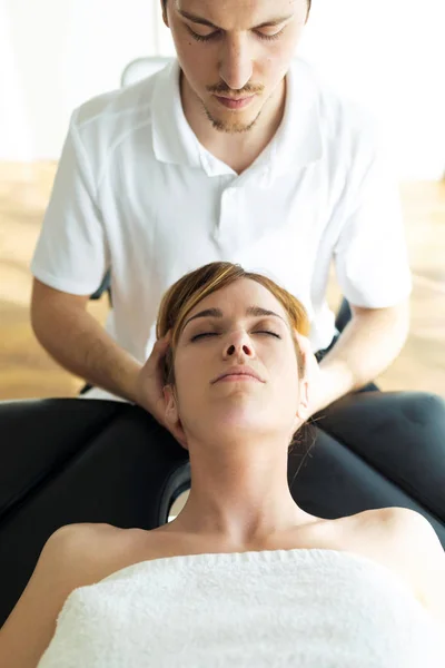 Mladý fyzioterapeut provádí léčbu krku pacientovi ve fyzioterapeutické místnosti. — Stock fotografie