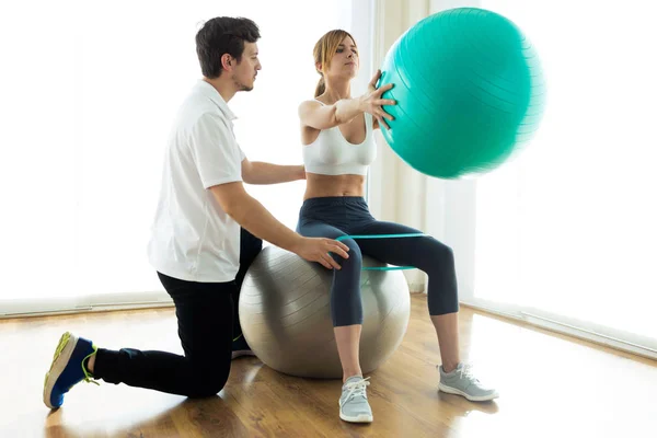 Fisioterapeuta ayudando al paciente a hacer ejercicio sobre la pelota de fitness en la sala de fisioterapia . —  Fotos de Stock