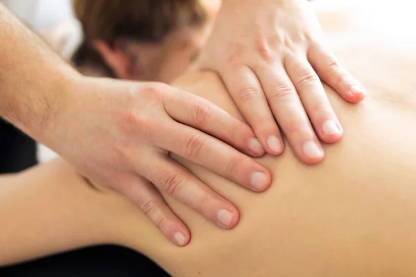 Joven fisioterapeuta haciendo un tratamiento de espalda al paciente en una sala de fisioterapia . — Foto de Stock