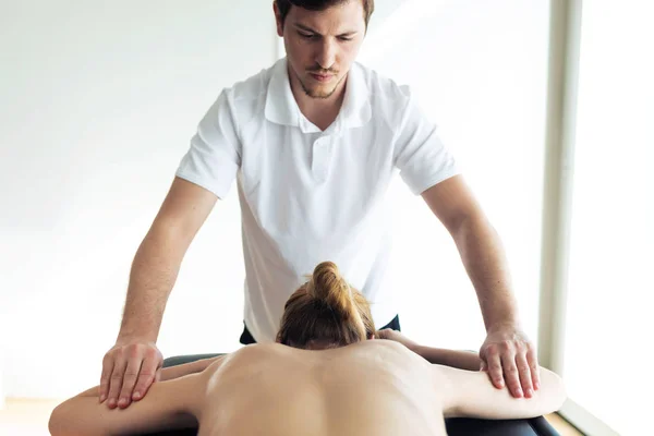 Joven fisioterapeuta haciendo tratamiento de brazos al paciente en una sala de fisioterapia . — Foto de Stock