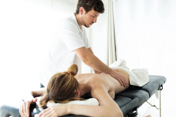 Young physiotherapist doing a back treatment to the patient in a physiotherapy room. — Stock Photo, Image