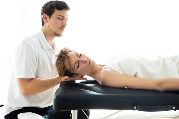 Joven fisioterapeuta haciendo un tratamiento del cuello al paciente en una sala de fisioterapia . —  Fotos de Stock