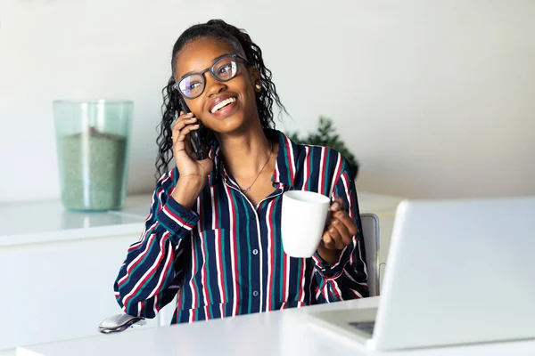 Бізнес молода жінка розмовляє по мобільному телефону під час пиття кави в офісі . — стокове фото