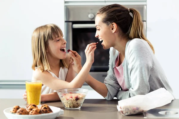 Красивая мать и дочь кормят друг друга злаками дома . — стоковое фото