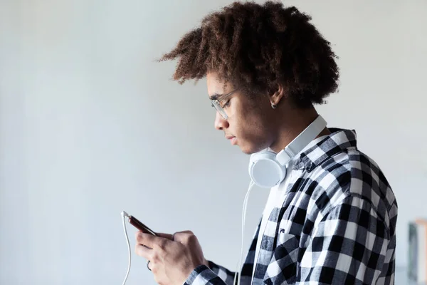 Beau jeune homme afro-américain utilisant son téléphone portable sur fond blanc . — Photo