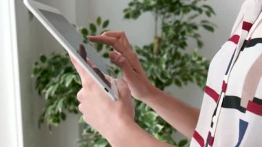 Ofiste dururken dijital tablet kullanan bir kadının ellerinin videosu.