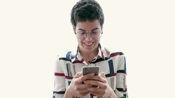 白い背景の上に立ちながら 携帯電話を使って笑顔の若いビジネスウーマンのビデオ — ストック動画