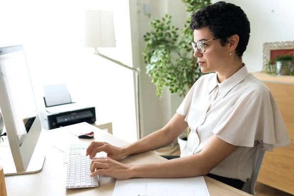 Koncentrerad ung affärskvinna som arbetar med sin bärbara dator på kontoret. — Stockfoto