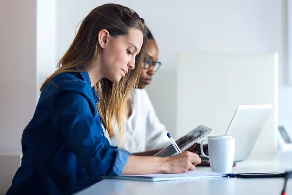 Duas mulheres de negócios muito jovens trabalhando com tablet digital e laptop no escritório . — Fotografia de Stock