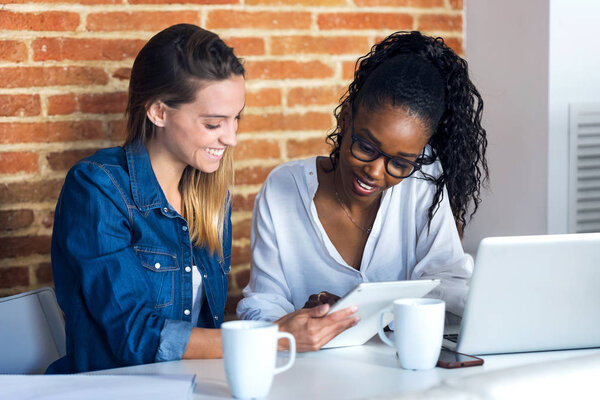 Две симпатичные молодые деловые женщины, работающие вместе с цифровым планшетом в офисе
.