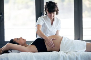 Spa merkezinde hamile kadın kadın fizyoterapist masaj karın.