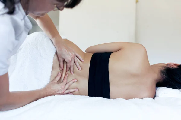 Female physiotherapist cures back pain of a pregnant woman in spa center. — Stock Photo, Image