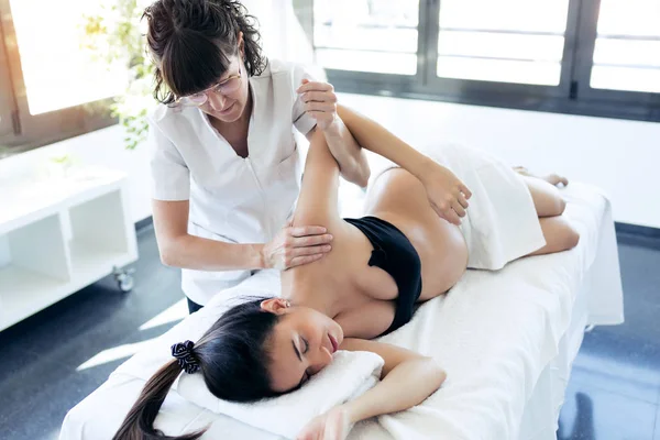 Physical therapist massaging pregnant woman's arm in spa center. — Stock Photo, Image