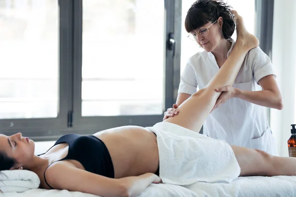 Массажист массирует ноги беременной женщины в спа-центре . — стоковое фото