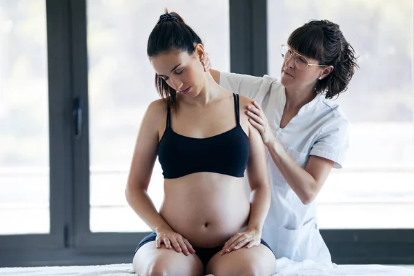 Physical therapist doing stretching to pregnant woman in a spa center. — Stock Photo, Image