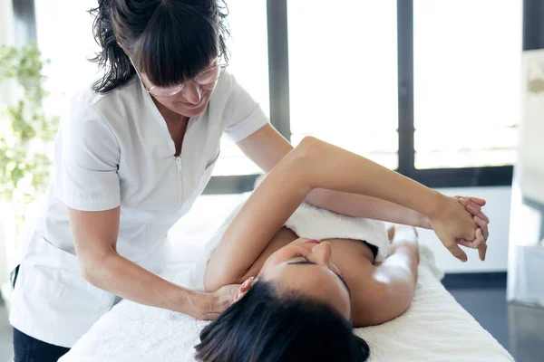 Physical therapist massaging pregnant woman's arm in spa center. — Stock Photo, Image