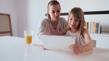 Pretty genç anne ve kızı evde dijital tablet kullanarak.