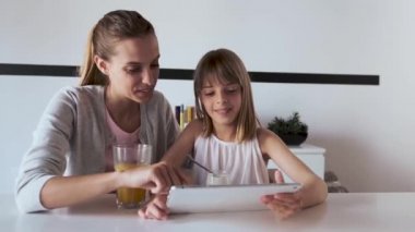 Pretty genç anne ve kızı evde dijital tablet kullanarak.