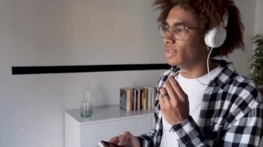 Yakışıklı genç afro-amerikan adam evde elleri serbest ve cep telefonu ile konuşuyor.