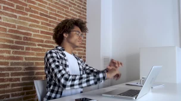 Trött ung afro-amerikansk man med glasögon stretching medan du arbetar med laptop hemma. — Stockvideo