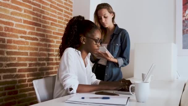 Dos mujeres de negocios bastante jóvenes que trabajan junto con tabletas digitales y portátiles en la oficina . — Vídeos de Stock