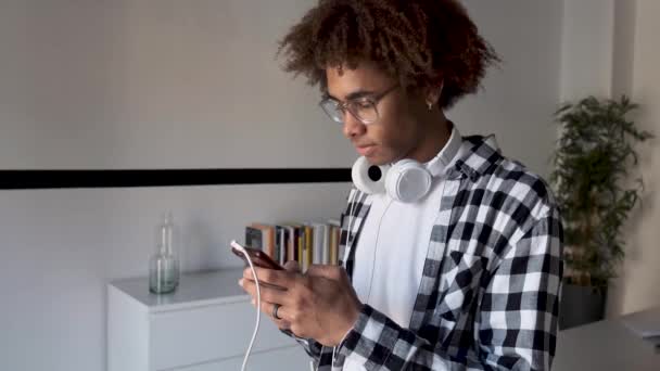 Yakışıklı genç afro-amerikan adam evde masada otururken cep telefonu kullanarak. — Stok video