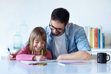 Kızı evde dizüstü çizim ile yakışıklı genç baba.