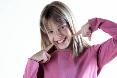 Mükemmel bir gülümseme ile güzel sarışın küçük kız kamera bakıyor. Beyaz arka planda yalıtılmış.