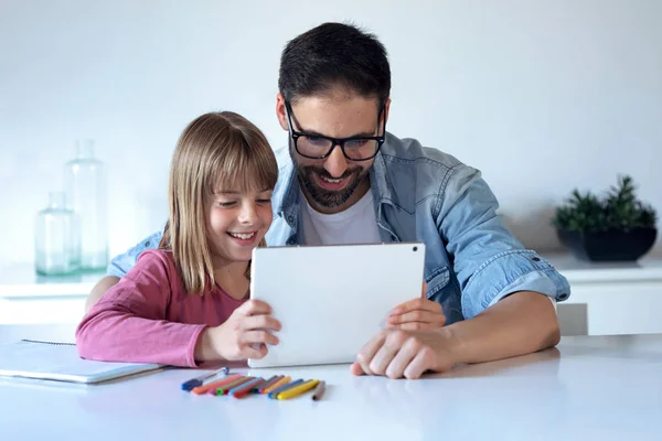 Hermoso joven padre con su hija pequeña usando la tableta digital en casa . — Foto de Stock