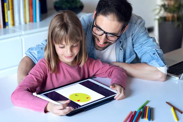 Bello il giovane padre con la figlia che disegna con tablet digitale a casa . — Foto Stock