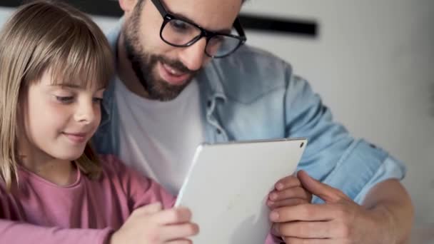 英俊的年轻父亲与他的女儿使用他们的数字平板电脑在家里. — 图库视频影像